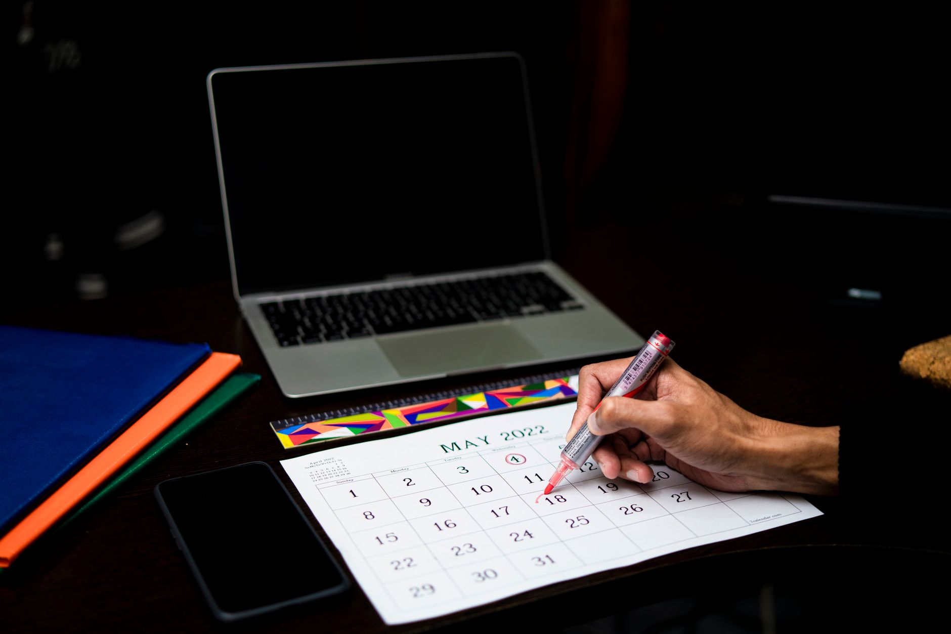 a person checking a calendar on a smartphone with a laptop nearby